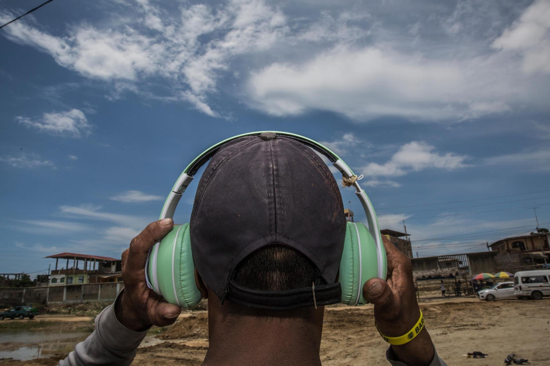 Carlos* gagne sa vie en vendant des bouteilles en plastique recyclées à Tumbes au Pérou. Grâce à cet argent, le Vénézuélien de 48 ans a pu s’acheter un casque avec lequel il écoute de la salsa. Pérou, mars 2022