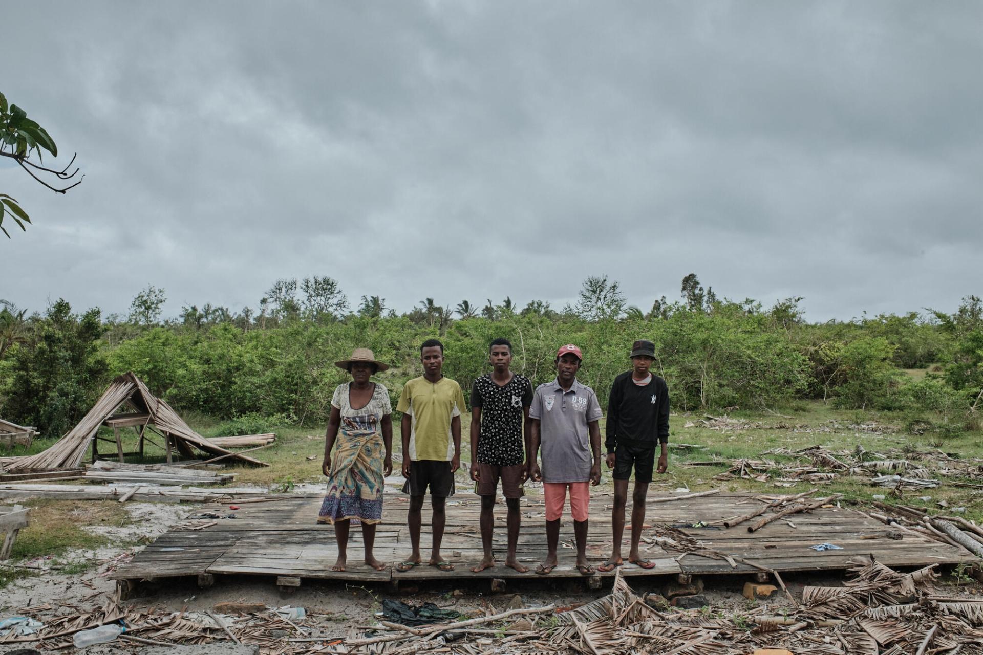 Portrait d’Aurélien Andriamanantena Tsiva avec sa famille devant leur maison de Nosy Varika, détruite par le cyclone Batsirai en février 2022. Madagascar, mars 2022