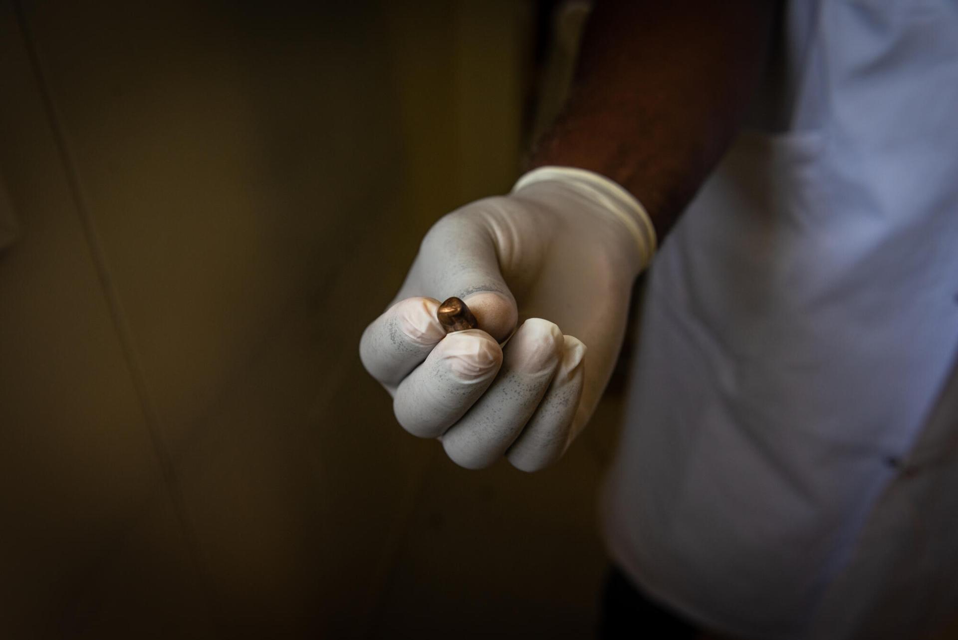 Un médecin montre le projectile qui vient d’être extrait du corps d’un patient, blessé par une balle perdue à Port-au-Prince. Haïti, juin 2022