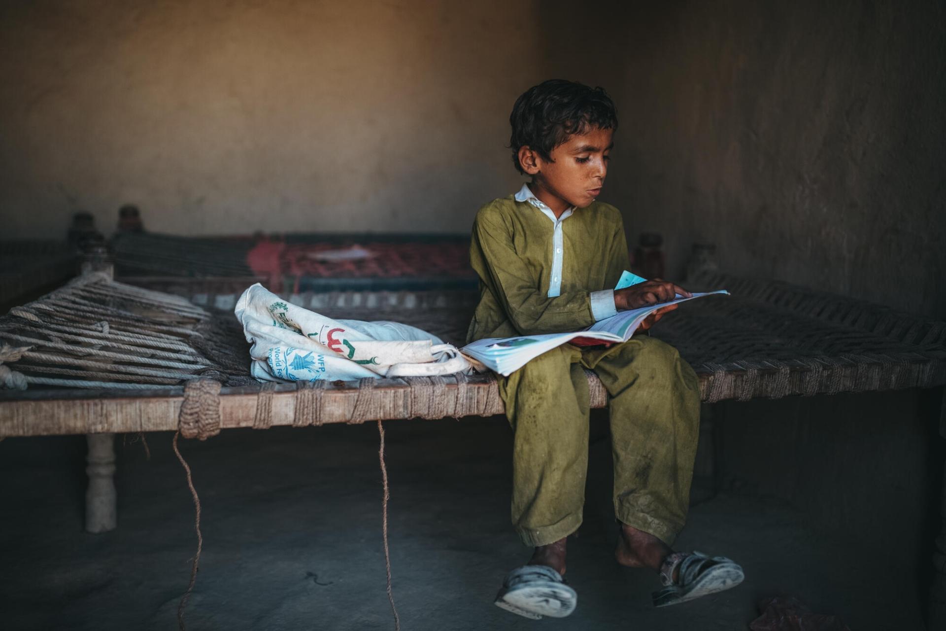 Un jeune garçon pakistanais fait ses devoirs dans la pièce qui sert d’abri aux six membres de sa famille. Leur maison, située dans le district de Dadu, a été détruite par des inondations historiques au Pakistan qui ont fait 1500 morts depuis le mois de juin. Pakistan, octobre 2022