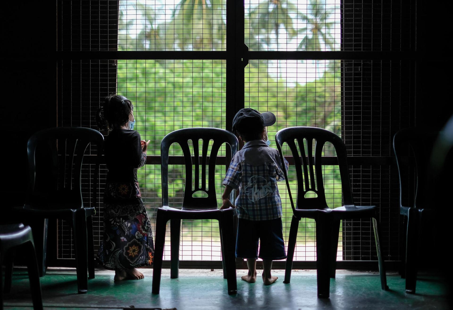 Des jumeaux regardent par la fenêtre de la salle d’attente de la clinique mobile de MSF, installée à Penang, en Malaisie. Les deux enfants appartiennent à la communauté rohingya, persécutée depuis plusieurs années au Myanmar. Malaisie, mai 2022