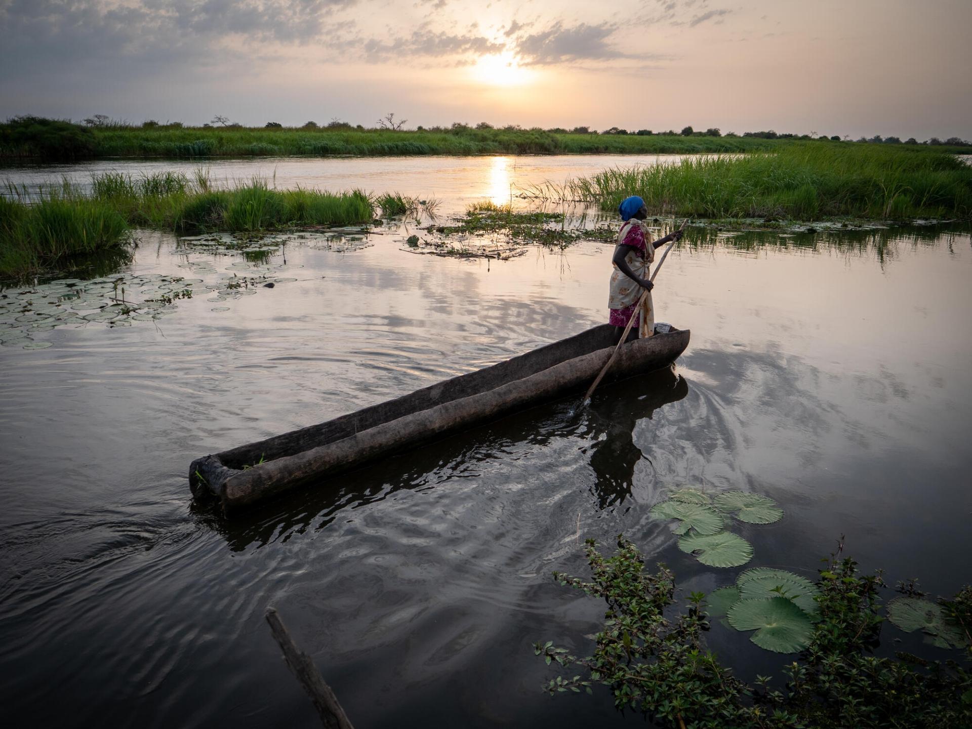 Une femme se déplace à bord d’une barque sur la rivière Zeraf, située près d’Old Fangak. Soudan du Sud, juin 2022