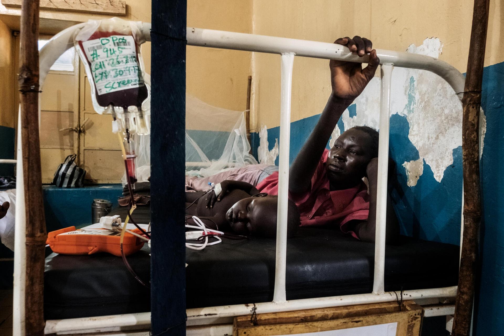 Agan et son fils dans un lit de l’hôpital général d’Aweil. L’enfant reçoit une transfusion.