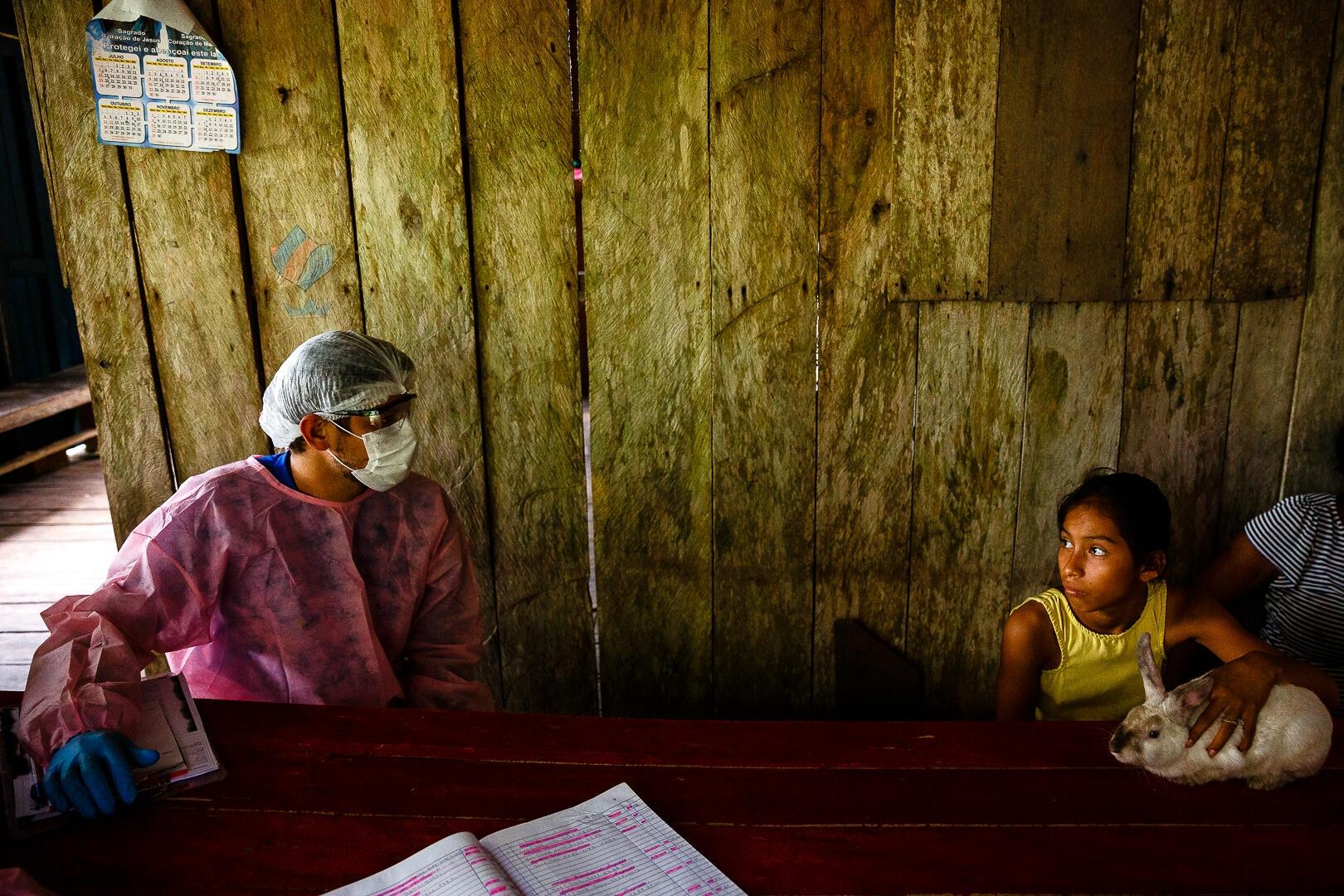 Un agent de santé municipal s’entretient avec une famille lors d’une visite à domicile dans la région du lac Mirini, État d’Amazonas, Brésil, juillet 2020.
