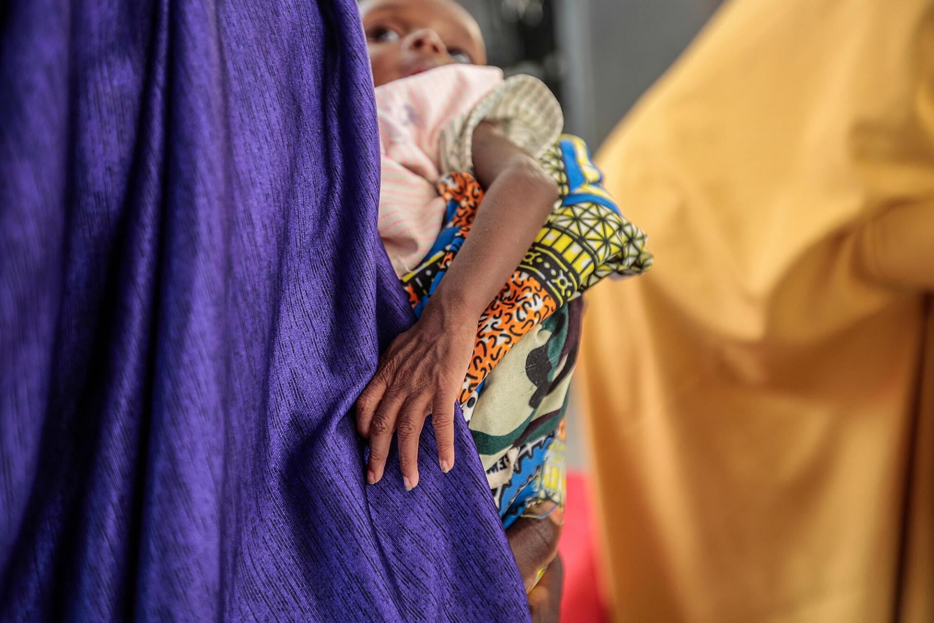 Fatima Isyaka (droite) place son bébé sur une balance afin de le peser. L’enfant souffre de malnutrition aiguë sévère, il est pris en charge au centre nutritionnel de MSF, État de Katsina, Nigeria, juin 2022.