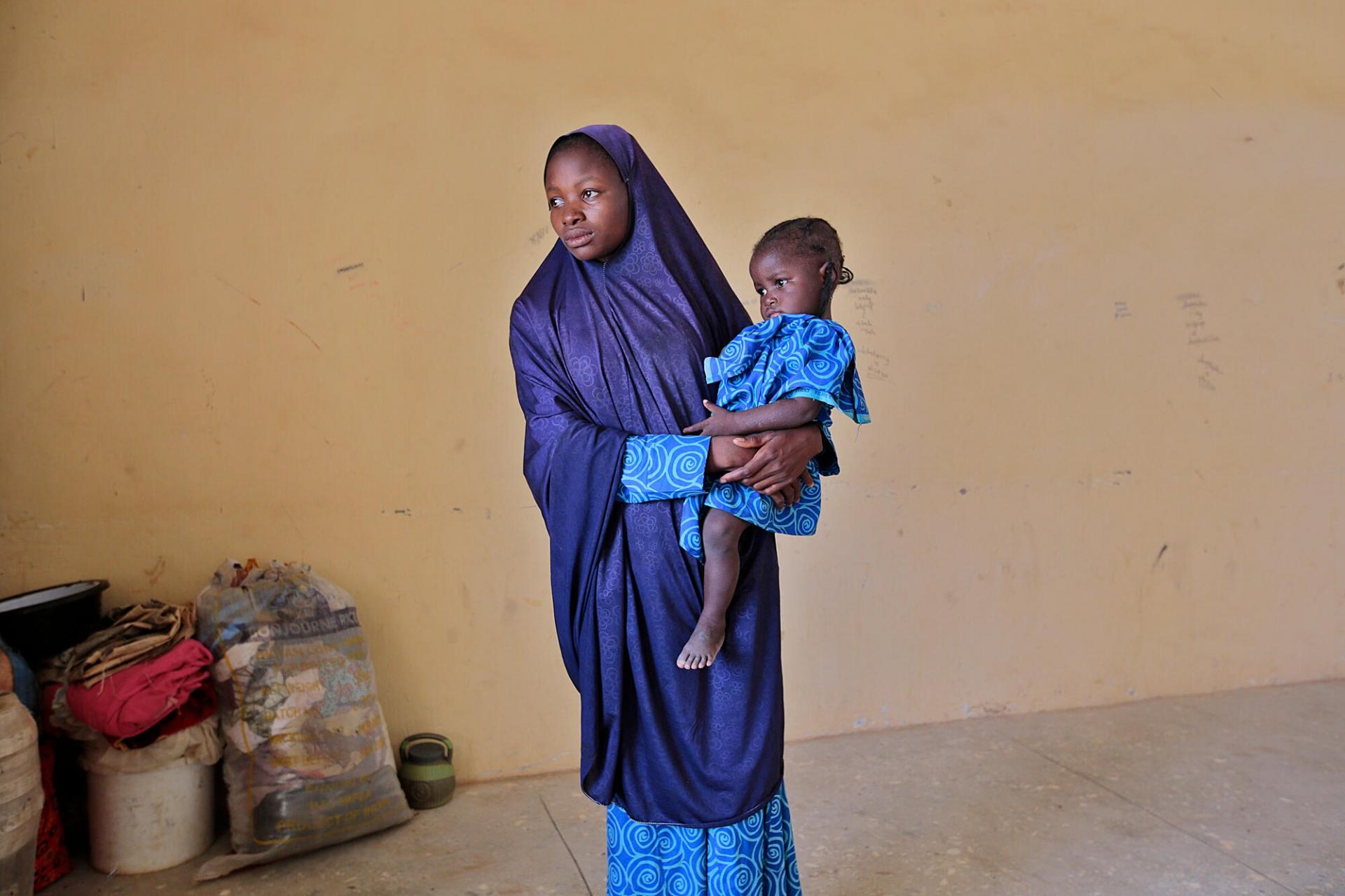 Portrait de Bashira Musa et sa fille. Elle a fui les violences des bandits dans son village natal pour se réfugier dans une école à Jibia.  Dans la région, les assassinats, viols, enlèvements contre rançon et attaques de gangs armés sont monnaie courante et menacent la vie de milliers de personnes. En 2021, 48% des enlèvements recensés au Nigeria se sont déroulés dans l’État de Katsina.  État de Katsina, Nigeria, juin 2022. 