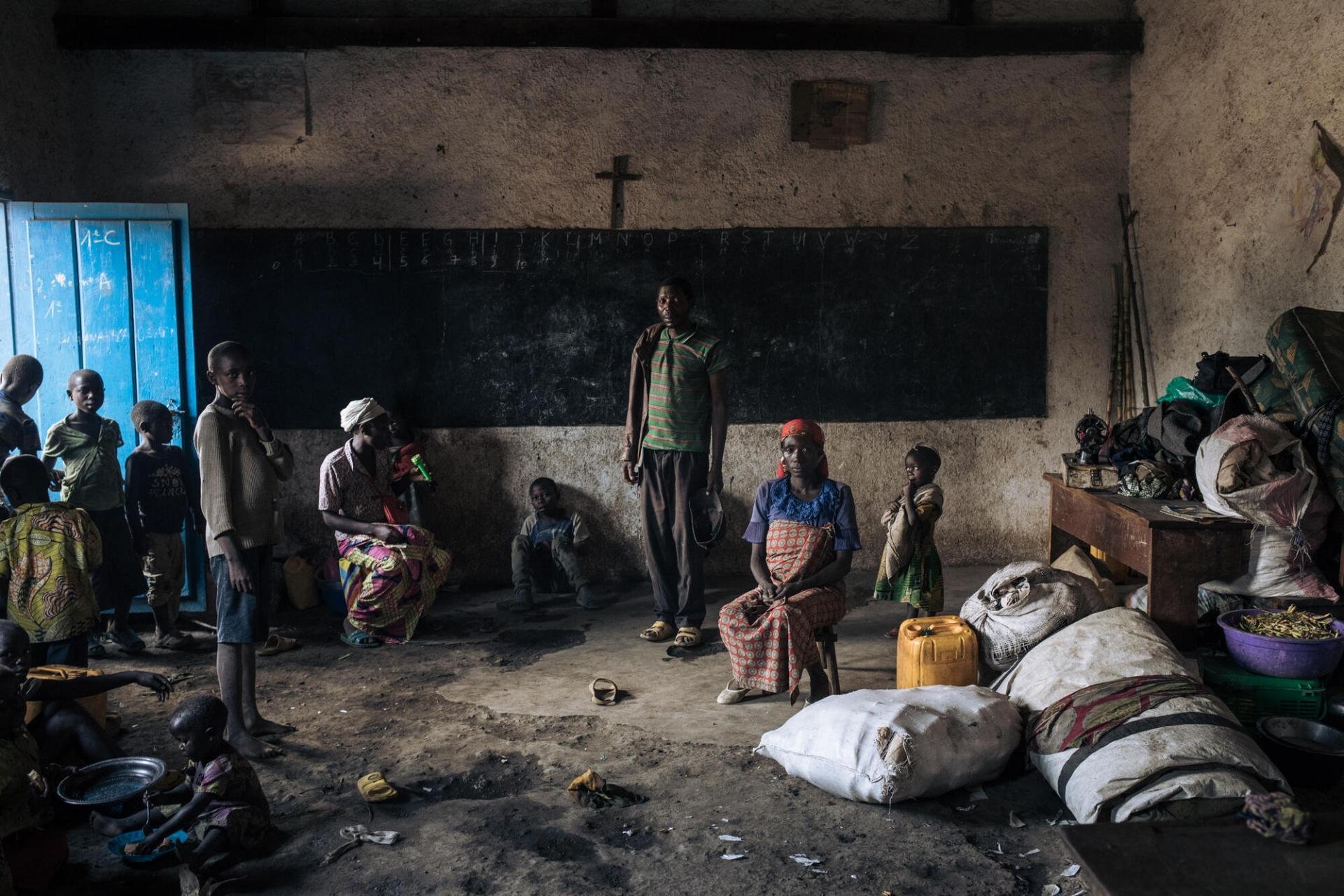 Des personnes déplacées, dont des enfants, se tiennent dans la salle de classe de l'école élémentaire de Rumangabo, qui a été transformée ces dernières semaines en un site de déplacés internes accueillant plus de 3 000 personnes.