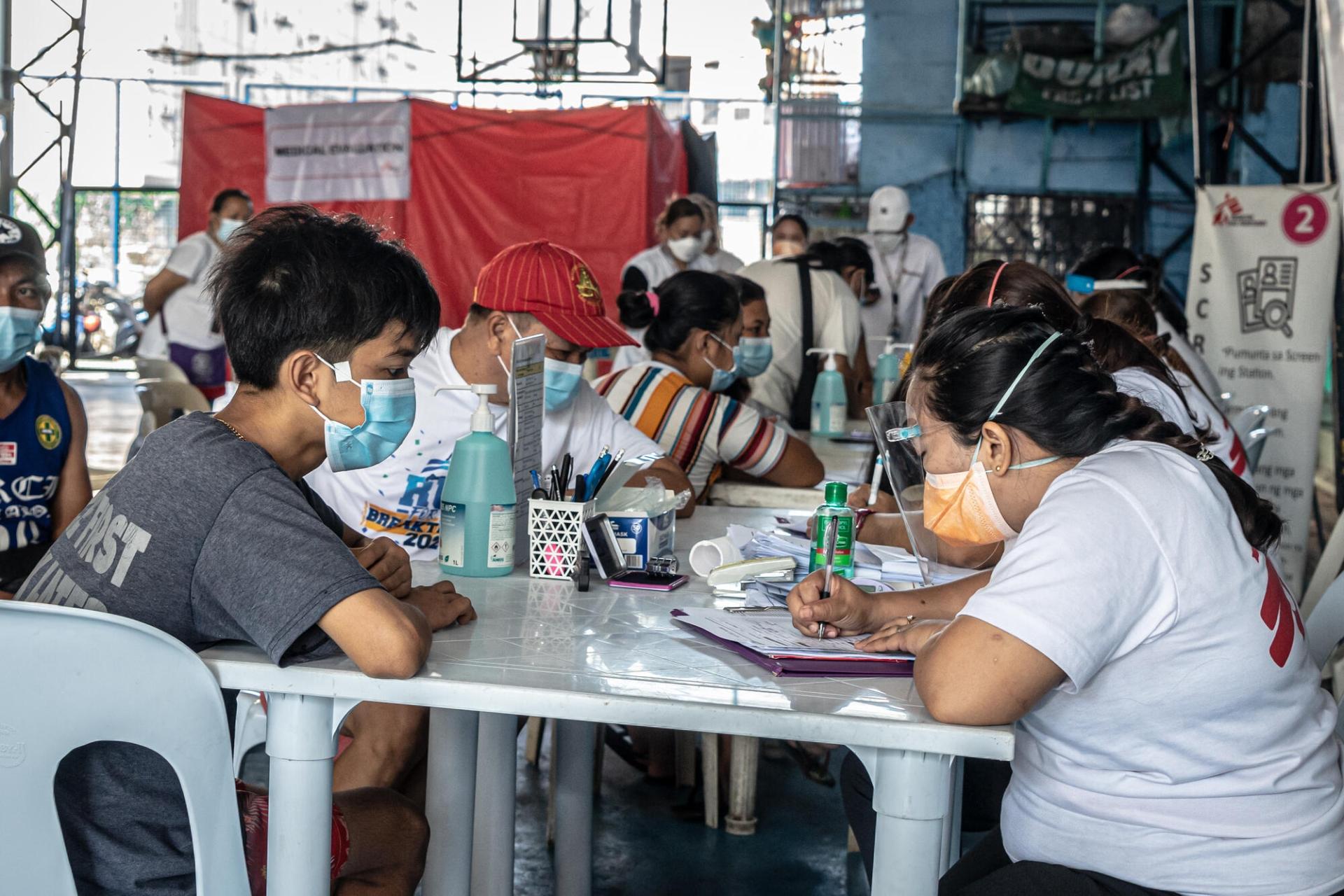 Des membres des équipes MSF en discussion avec des personnes qui souhaitent se faire dépister contre la tuberculose. Tondo, Manille. Philippines. 1er mars 2023.