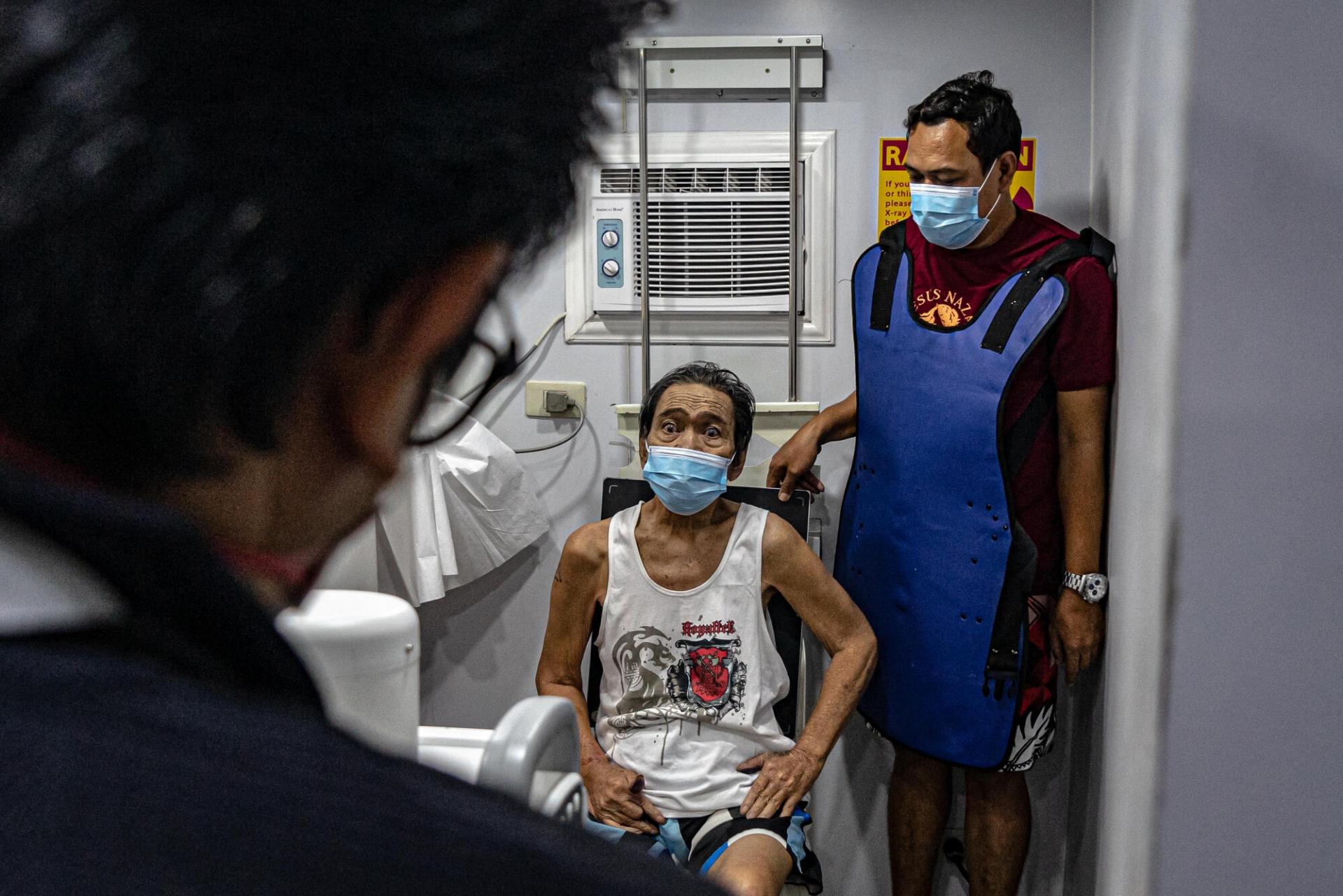 Un patient et son fils lors d'un dépistage de la tuberculose, à l'aide de radiographie. Manille. Philippines. 13 mars 2023.