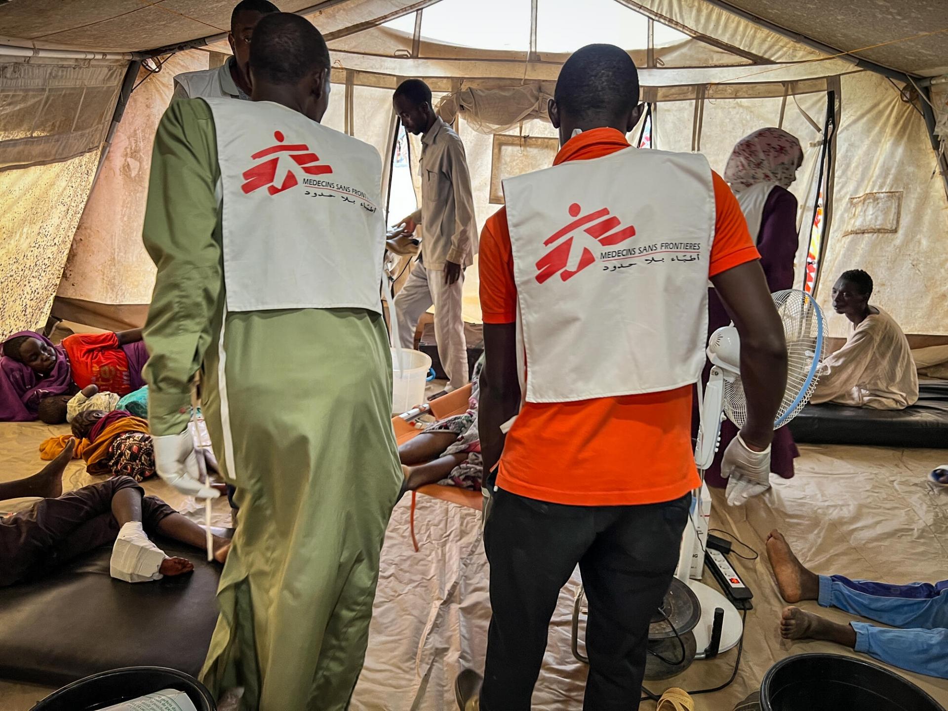 Des membres des équipes MSF transportant un patient dans une tente de l'hôpital d'Adré, lors de la vague d'afflux de blessés des 15,16 et 17 juin. Tchad. 