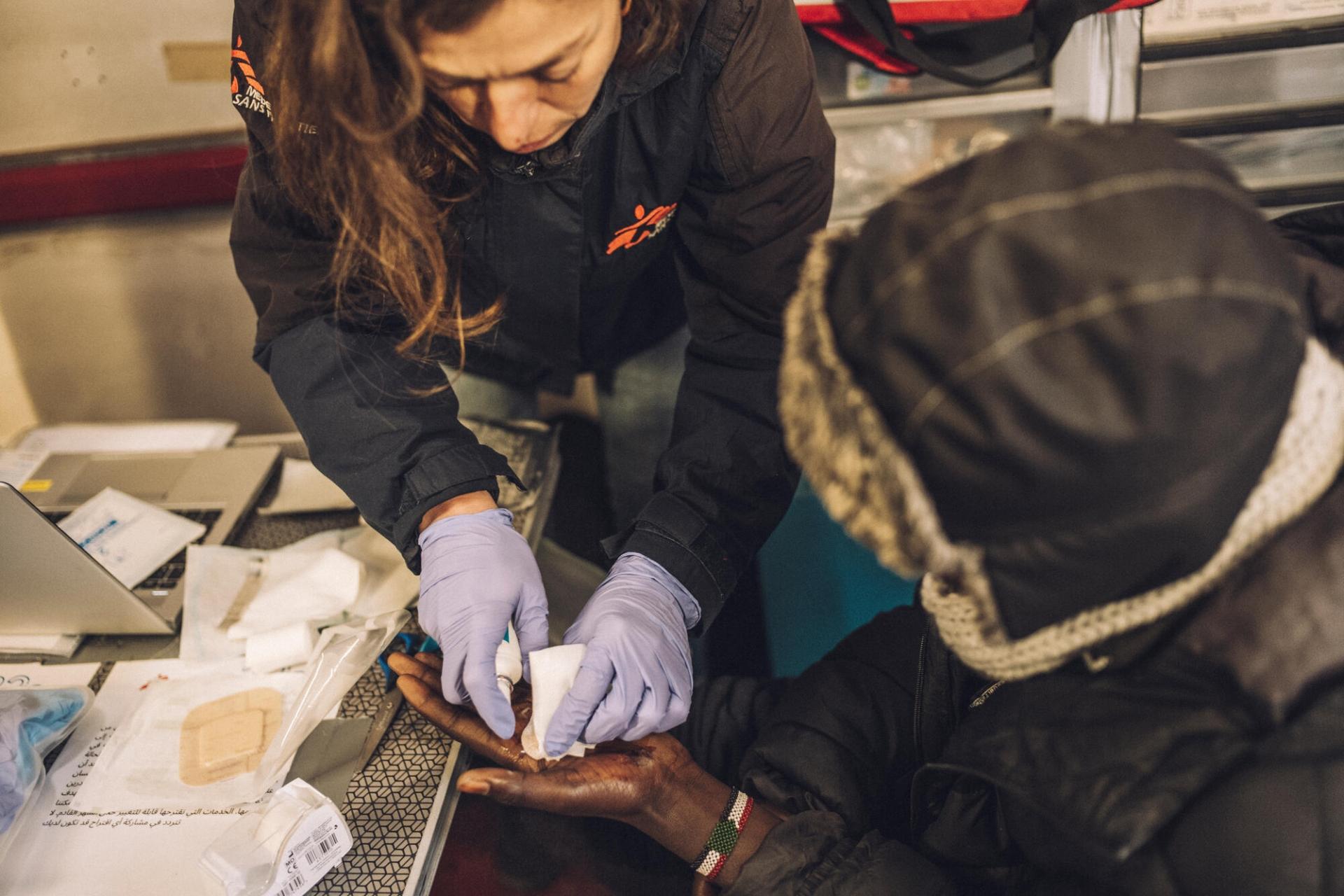 Une infirmière MSF prodigue des soins à la main d’un migrant d’origine soudanaise. Les traumatismes physiques et les petites excoriations sont très fréquents parmi les personnes exilées qui survivent dans des campements insalubres et tentent quotidiennement de monter à bord de camions en direction du Royaume-Uni.