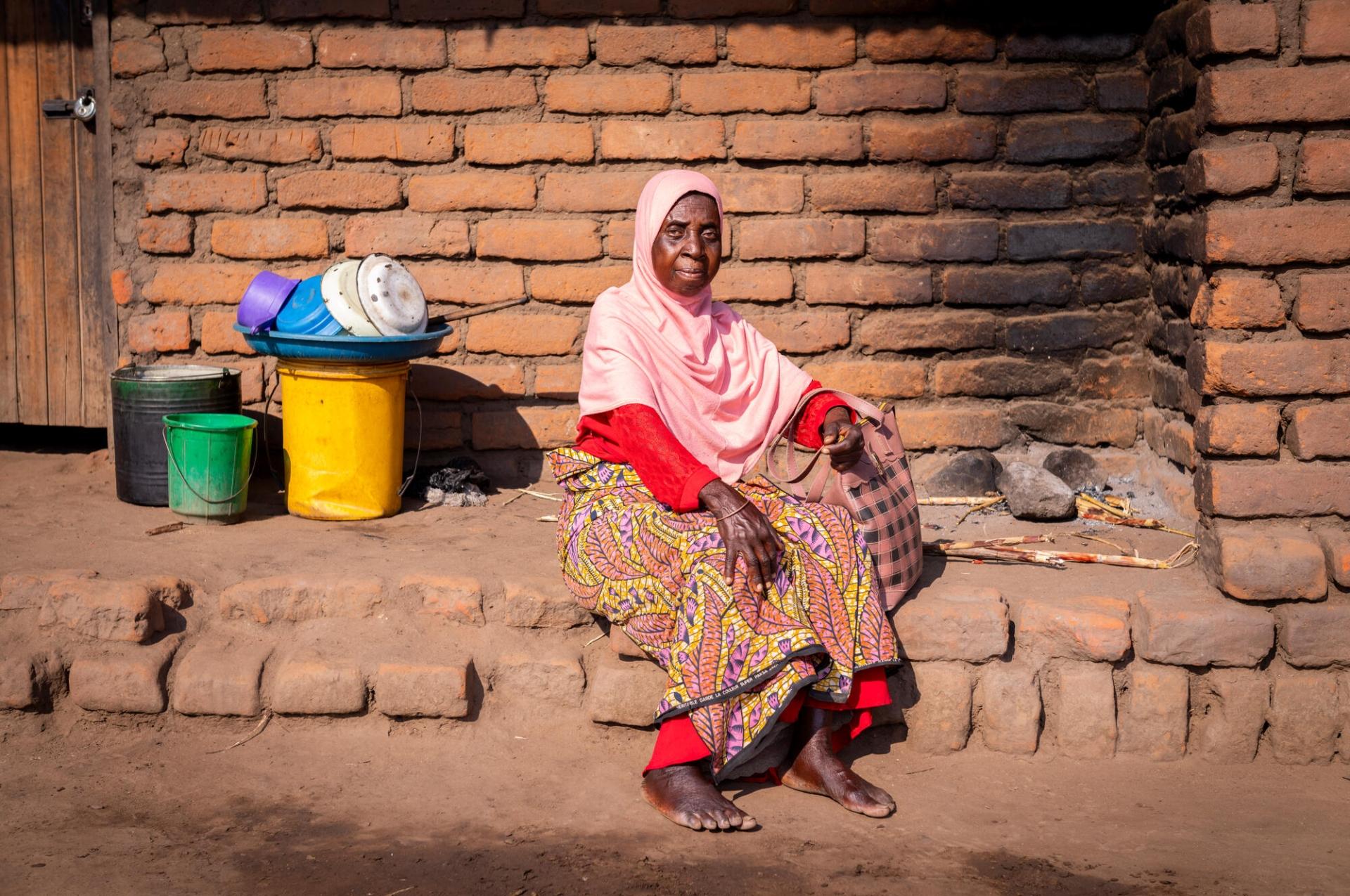 Une patiente soutenue par MSF assise devant sa maison dans son village au Malawi