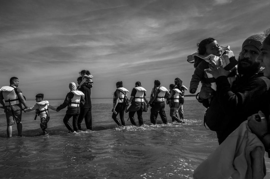 Un groupe d’exilés progresse dans l’eau pour rejoindre un bateau pneumatique, dans le but de traverser la Manche, à Grand-Fort-Philippe, en France.