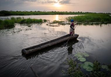 Une femme se déplace à bord d’une barque sur la rivière Zeraf, située près d’Old Fangak. Soudan du Sud, juin 2022