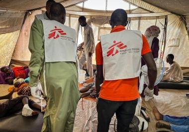 Des membres des équipes MSF transportant un patient dans une tente de l'hôpital d'Adré, lors de la vague d'afflux de blessés des 15,16 et 17 juin. Tchad. 