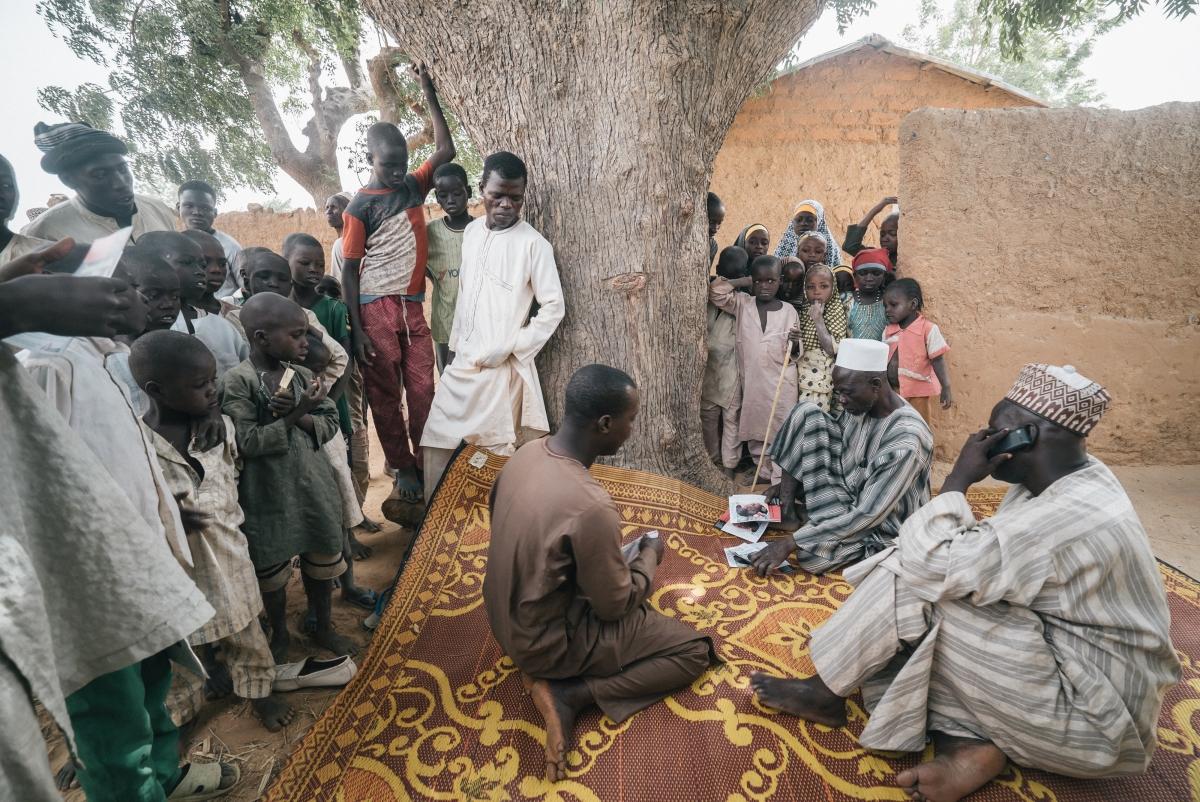 L'équipe de sensibilisation de l'hôpital de Sokoto a commencé à rechercher activement des cas dans l'État de Sokoto en janvier 2017. Ici, dans un village du gouvernement local de Dange-Shuni, l'équipe montre des brochures à la communauté locale pour vérifier s'il y a des personnes infectées par la maladie dans la région. Ils informent également les gens sur les causes du noma et sur l'importance d'un traitement dès les premiers stades de la maladie.
 © Claire Jeantet - Fabrice Caterini/INEDIZ