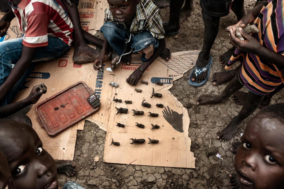 Des enfants fabriquent des figurines de bétail en boue. Près de 40 % de la population du camp de protection des civils est âgée de moins de cinq ans.
 © Peter Bauza