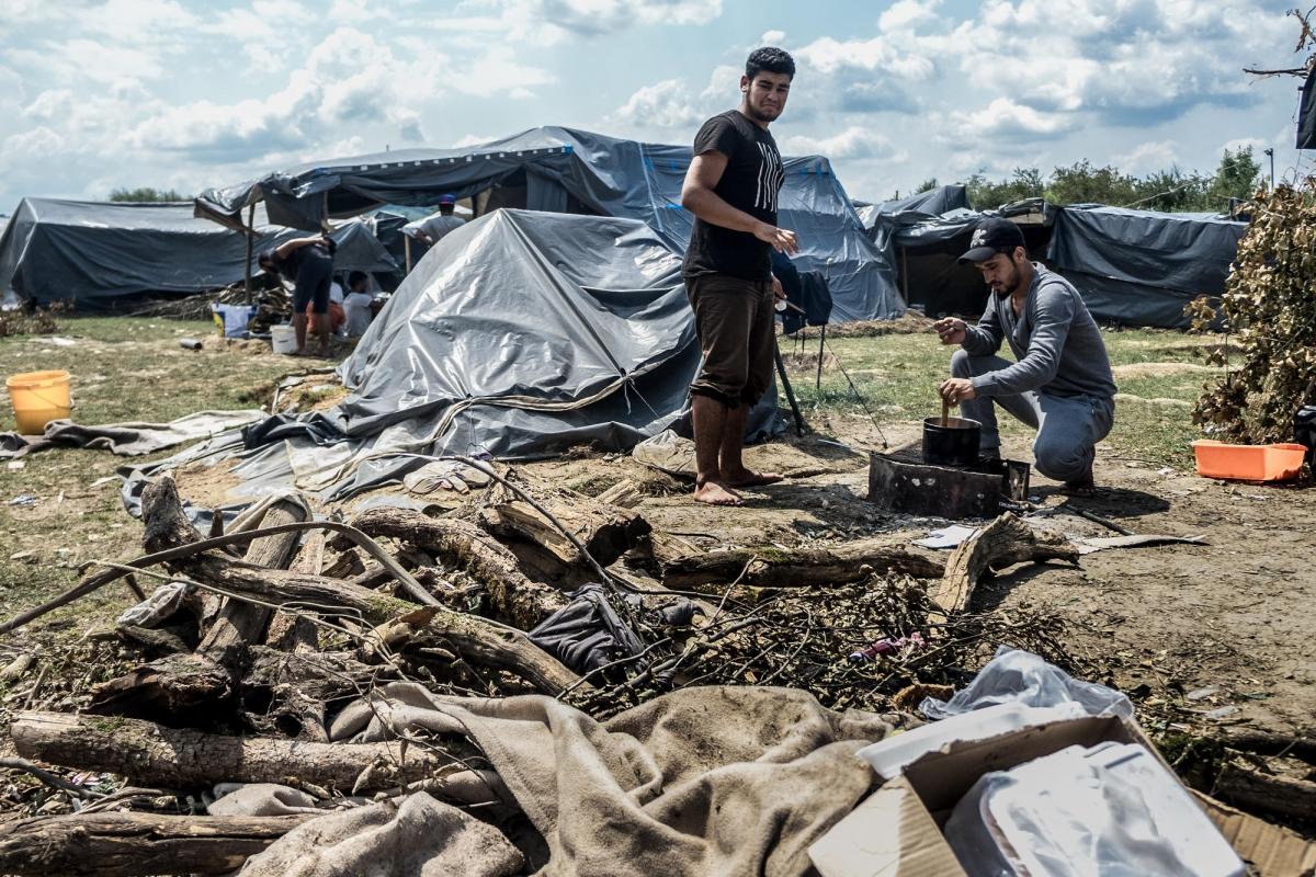 Deux hommes originaires de Syrie cuisinent avec des matériaux de récupération dans un&nbsp;camp&nbsp;informel près de Velika Kladuša. Bosnie-Herzégovine. 2018.
 © Kamila Stepien