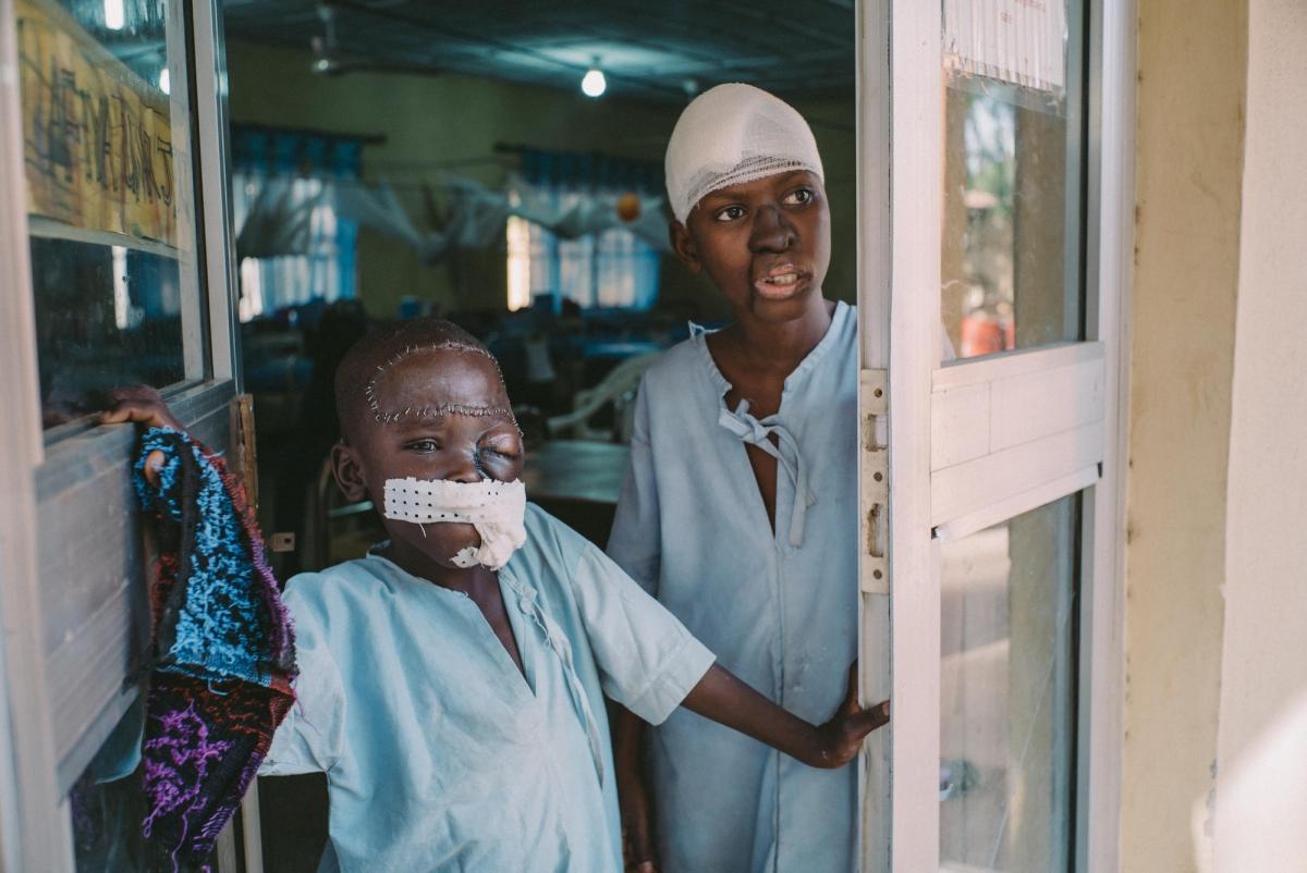 Umar a 8 ans et il vient de l'État de Kano. Il se tient à l'entrée de l'unité de soins post-opératoires de l'hôpital de Sokot, avec un autre patient âgé de 15 ans. Nigeria. 2017.
 © Claire Jeantet - Fabrice Caterini/INEDIZ