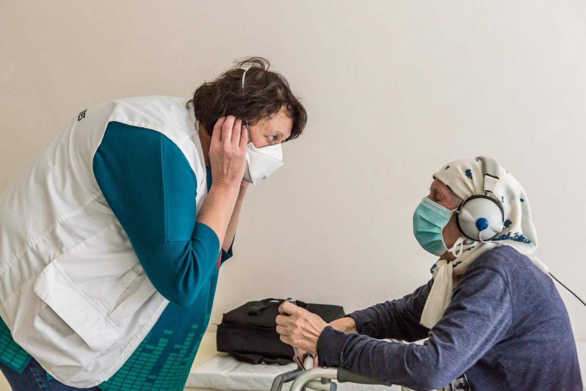 Olena est une infirmière MSF. Elle effectue des tests d'audition sur une patiente. Elle s'appelle Lidjia et a 78 ans. Ukraine. 2018.
 © Oksana Parafeniuk