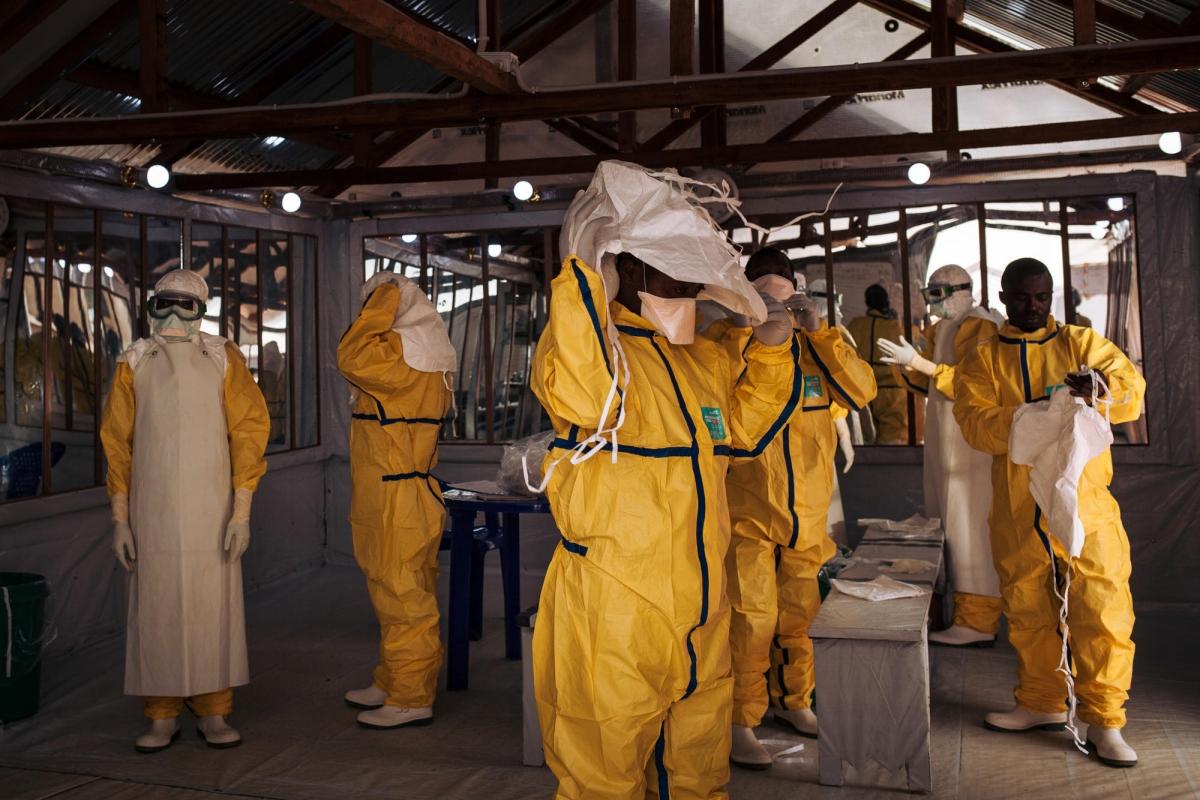 Des travailleurs de santé MSF revêtent leur équipement de protection individuel avant d'entrer dans la zone à risque du centre de traitement Ebola. République démocratique du Congo. 2018.&nbsp;
 © Alexis Huguet