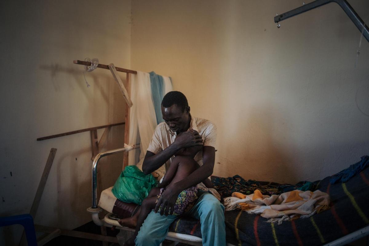 Un père tient sa fille de deux ans&nbsp;souffrant de la rougeole, dans l'unité de rougeole dirigée par MSF à l'hôpital de Biringi, dans la province d'Ituri, au Nord-Est de la République démocratique du Congo.
 © Alexis Huguet