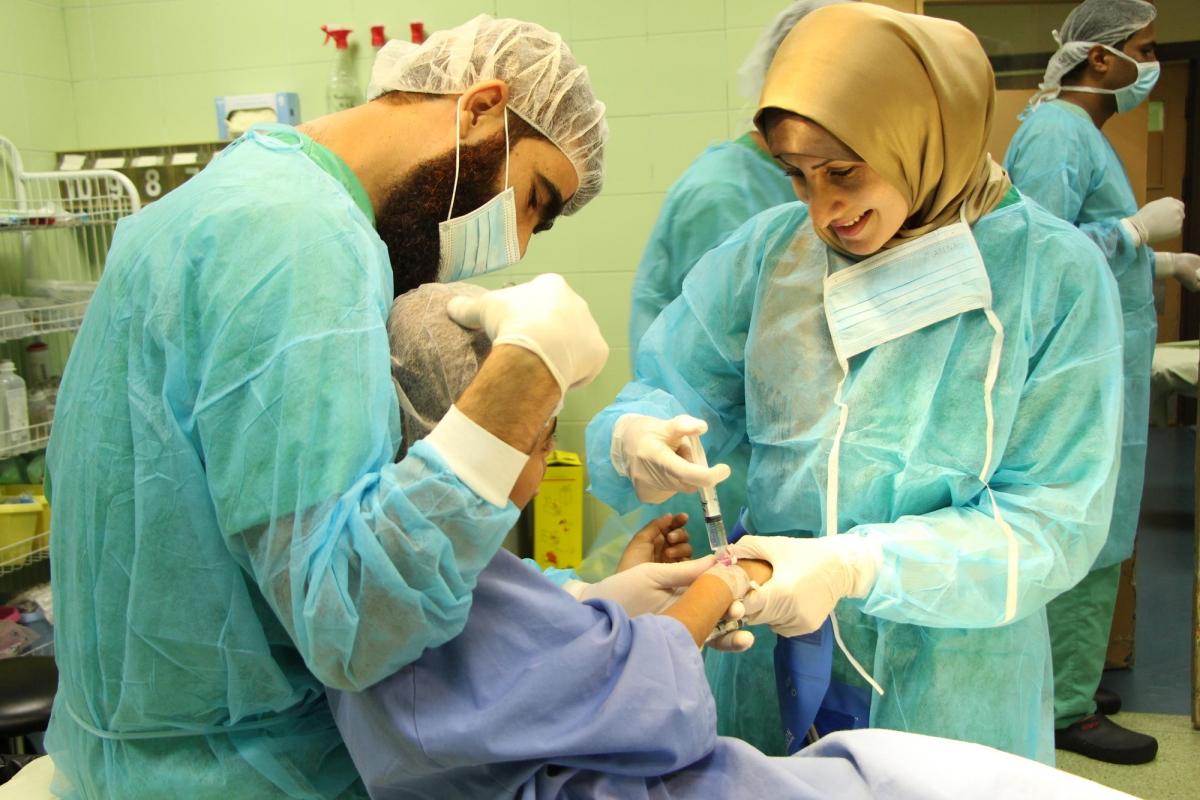 Rima Alghoul, anesthésiste MSF, prend soin de Salwa, 11 ans, avant une intervention chirurgicale pour nettoyer et panser sa blessure, à l'hôpital Dar Al Salam à Gaza.
 © Candida Lobes/MSF