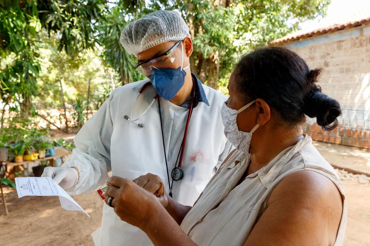 Le docteur Pedro Ueda explique la prescription médicale à une patiente du village indigène de Lagoinha, dans l'État du Mato Grosso do Sul. Elle et son mari ont contracté le coronavirus et sont restés isolés chez eux. Ils ont reçu un suivi médical à domicile.
 © Diego Baravelli/MSF