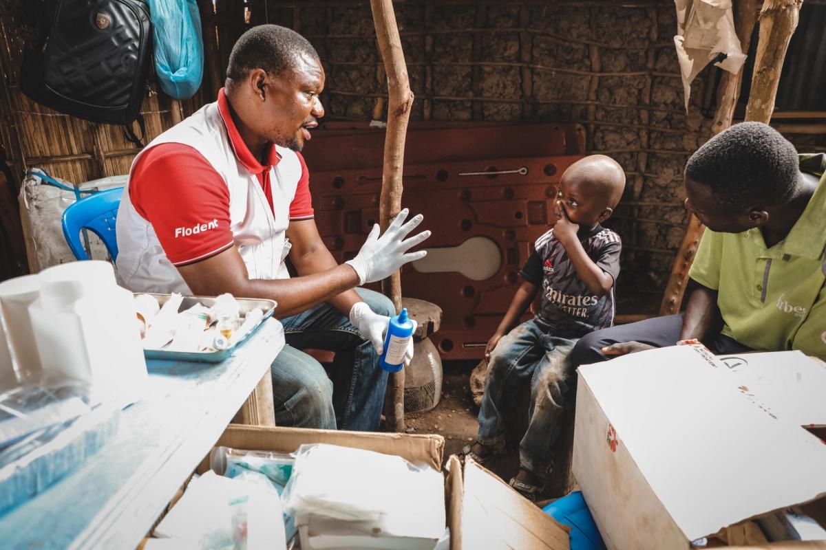 Evariste Bayedi, infirmier MSF, prodigue des soins au fils de Mayunga Papy sur le site de déplacés de Simbambili, à Kwamouth. Mayunga Papy prévoyait de vendre sa parcelle de terre pour emmener son fils voir un médecin à Kinshasa, mais l'arrivée de la clinique mobile MSF lui a permis de faire soigner son fils gratuitement.
 © Johnny Vianney Bissakonou/MSF