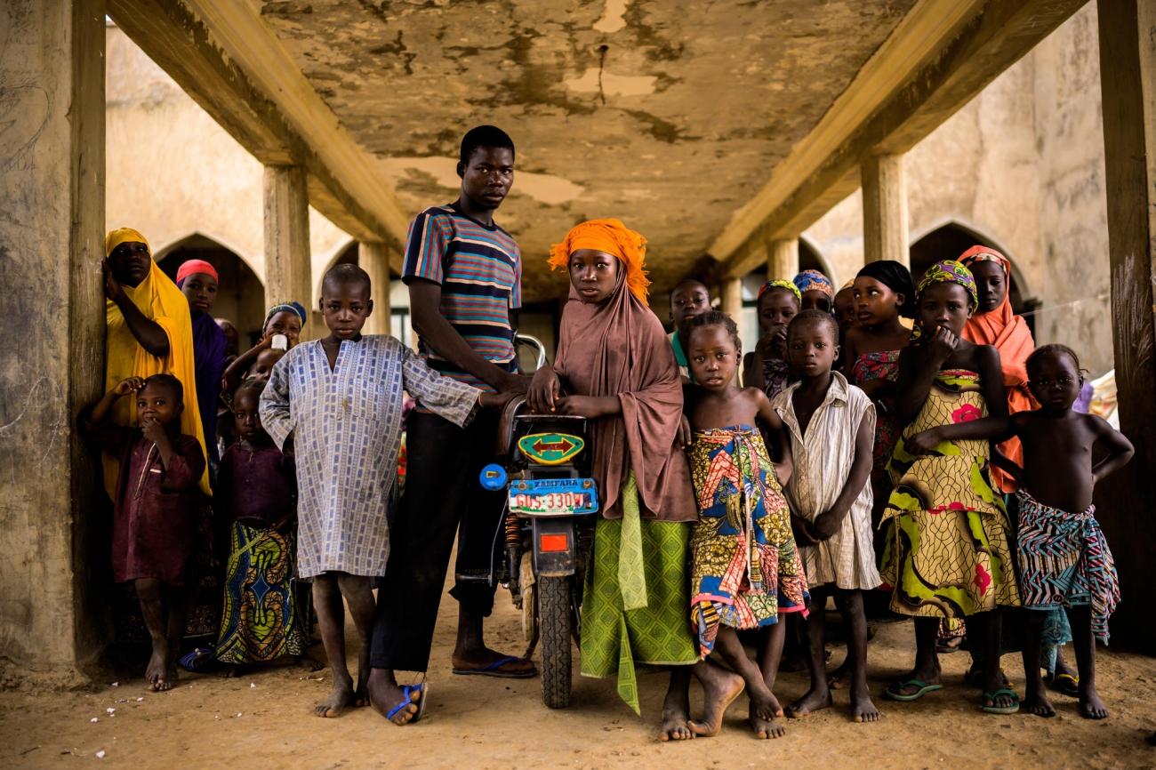 Des personnes déplacées dans la ville d'Anka. La jeune femme au foulard orange vivait à une journée de marche d'Anka avant l'attaque de son village. Elle habite dans un squat depuis un et demi avec ses parents et ses huit frères et sœurs. Nigeria. 2019.
© Benedicte Kurzen/NOOR