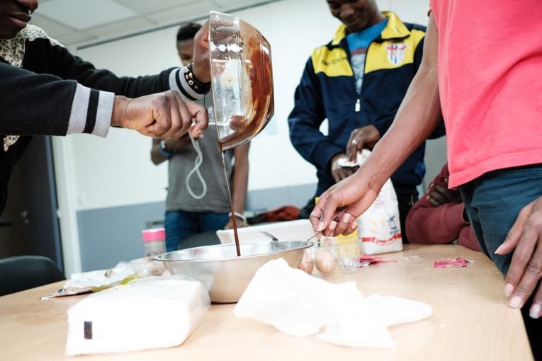 Des jeunes participent à un atelier cuisine et pâtisserie avec un membre de l’équipe de MSF du projet Passerelle.
 © Augustin Le Gall