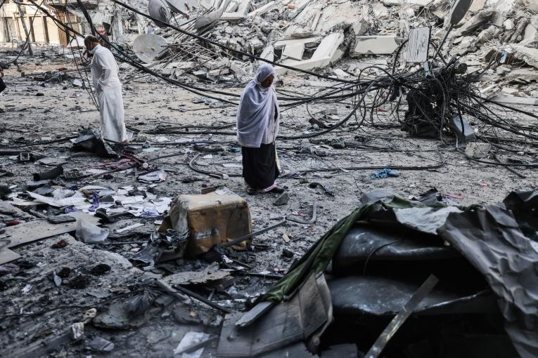 Après avoir célébré les prières de l'Aïd al-Fitr, des Palestiniens marchent au milieu des débris près de la tour al-Sharouk, qui abritait le bureau de la chaîne de télévision Al-Aqsa dans la bande de Gaza. La tour a été détruite par un bombardement israélien. Ville de Gaza, le 13 mai 2021.
 © Mohammed Abed/AFP