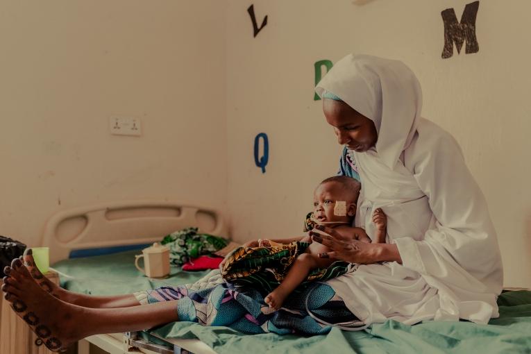 Yusuf Malami, âgé de 7 mois, dans les bras de sa mère, Hadiza Malami. Yusuf, qui souffre de malnutrition, a fait plusieurs séjours à l'hôpital, mais montre des signes d'amélioration. Hôpital général de Shinkafi, État de Zamfara, Nigeria. 27 mars 2026.
 © Nnoli Amarachi