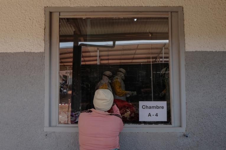 Denise, regarde une équipe médicale de MSF s'occuper de sa jeune sœur, suspectée d'avoir été infectée par le virus Bundibugyo.
 © Paul Lorgerie/MSF