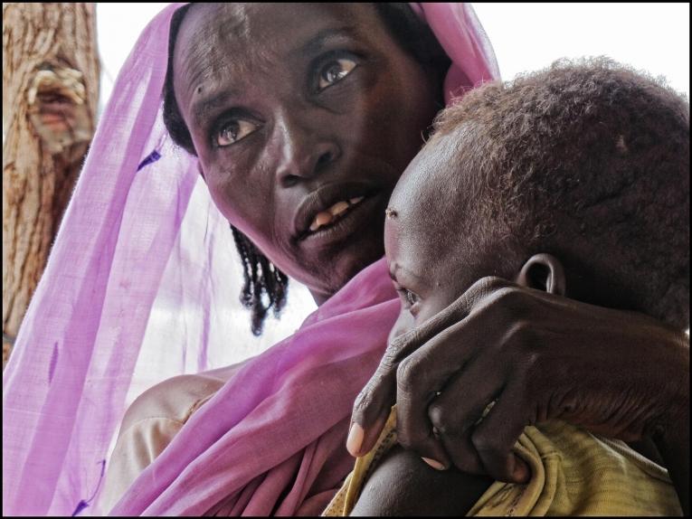 Une femme tient son enfant dans les bras, en attendant de recevoir des soins médicaux dans un centre de santé MSF au Nord-Darfour. Soudan. 2014
 © MSF