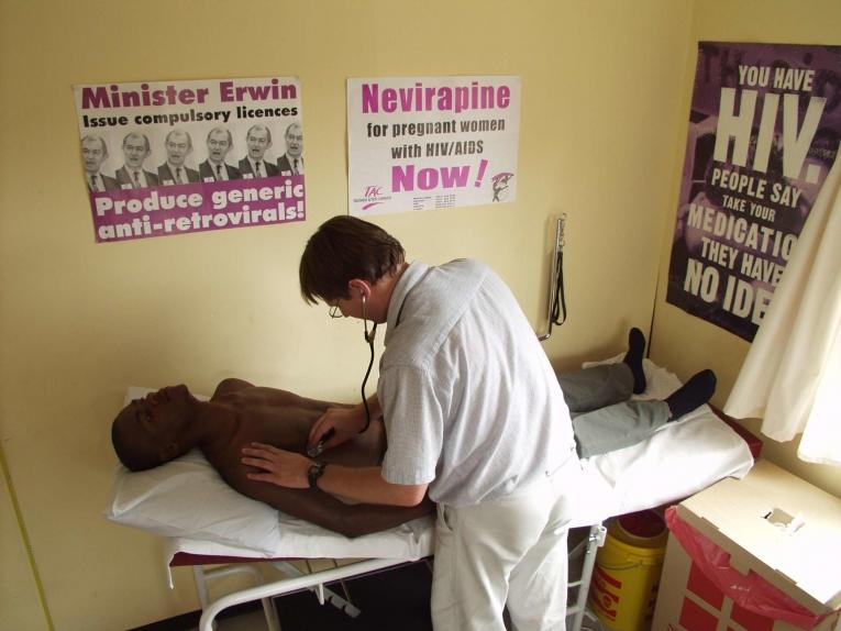 Début des années 2000. Un médecin de MSF examine un patient à Khayelitsha. Les posters sur le mur témoignent des actions en faveur d’un accès facilité aux traitements contre le VIH.
 © Sebastian Charles