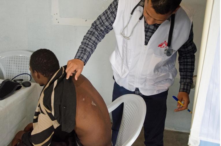 Un médecin MSF ausculte un patient dans une salle de consultation aménagée dans un foyer pour migrants dans la ville de Beni Walid. En collaboration avec une ONG locale, MSF organise des consultations dans ce foyer et des références vers d'autres hôpitaux pour les cas médicaux les plus graves.&nbsp;
 © Christophe Biteau/MSF