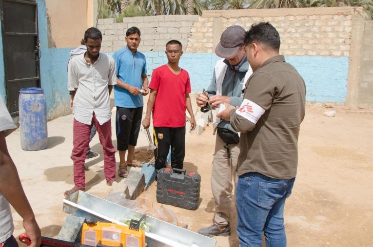 Une équipe de logisticiens MSF dans le centre de détention de Khoms est en train de fixer des lave-mains et échange avec les migrants qui sont détenus. Les conséquences médicales d’un mauvais accès à l’eau potable, telles que les diarrhées, sont parmi les principales pathologies vues en consultation dans les centres de Khoms et Misrata.&nbsp;
 © Christophe Biteau/MSF