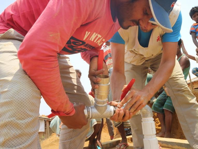 Arafat Hosen (à gauche),&nbsp;superviseur du réseau de distribution d’eau chez MSF, et Thibault Chazal, logisticien MSF, conduisent l'installation d'une pompe à eau submersible dans un puit profond.
 © MSF