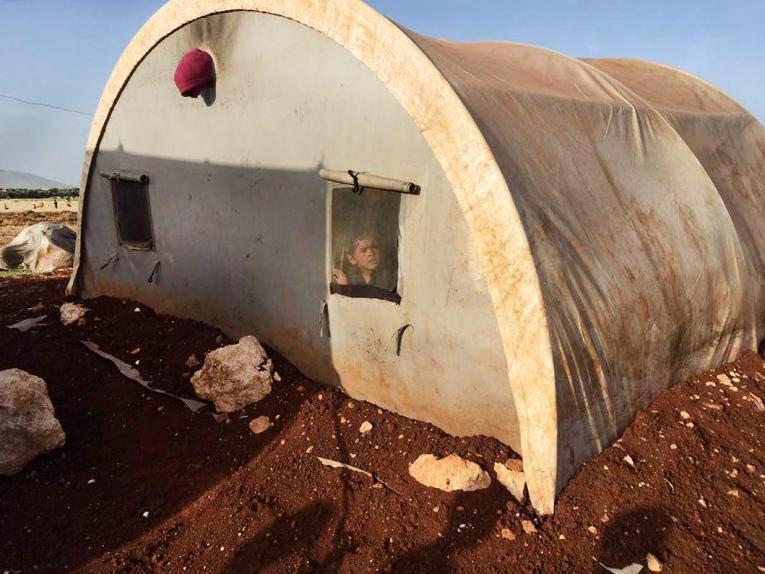 Un jeune Syrien regarde à travers la fenêtre d'une tente dans un camp de personnes déplacées d'Idlib en Syrie.&nbsp;
 © Mohammed  Homidan/MSF