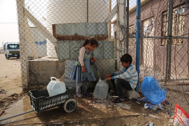 Des enfants remplissent des bidons d'eau dans le camp d'Amriya Falloujah. Irak. 2018.
 © Mohammad Ghannam/MSF