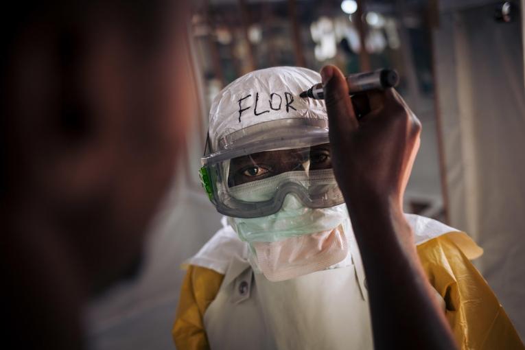 Un travailleur de santé MSF revêt son équipement de protection personnel avant d'entrer dans la zone à risque du centre de traitement Ebola. Leurs noms sont systématiquement écrits sur leur équipement. 2018. République démocratique du Congo.
© Alexis Huguet