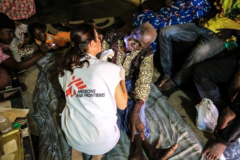 L'infirmière Nathalie Kornfein change le pansement de Maady Dabo, un patient âgé de 76 ans&nbsp;atteint d'un cancer oral. Pendant les soins, il est entouré par sa famille. Mali. 2019.&nbsp;
 © MSF/Mohammad Ghannam