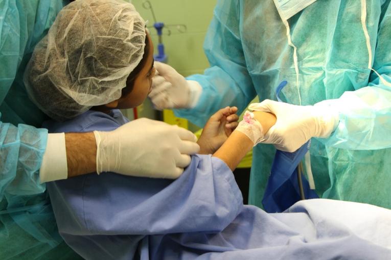 Rima Alghoul, anesthésiste MSF, prend soin de Salwa, 11 ans, avant une intervention chirurgicale pour nettoyer et panser sa blessure, à l'hôpital Dar Al Salam à Gaza.
 © Candida Lobes/MSF