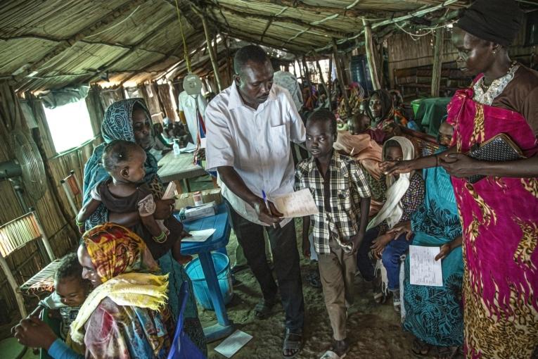 Un enfant, accompagné d'un membre du personnel MSF dans la zone de triage du nouvel hôpital MSF du camp de réfugiés d'Al Kashafa, dans l'État du Nil blanc, au Soudan.
 © MSF/Igor Barbero