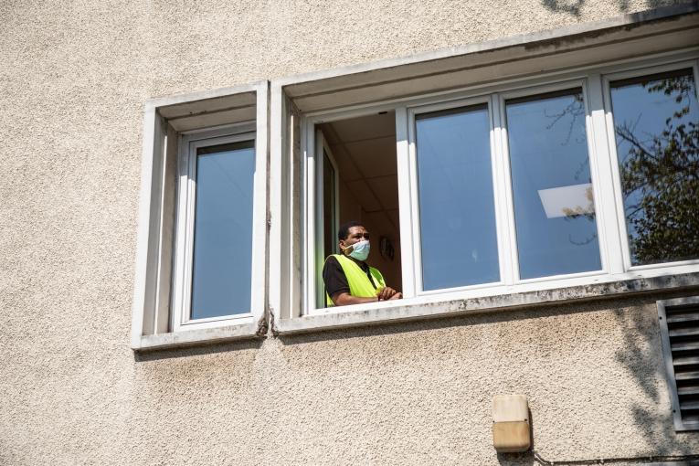 L'un des agents de sécurité du centre, à la fenêtre du premier étage. Paris, avril 2020.
 © Agnes Varraine-Leca/MSF