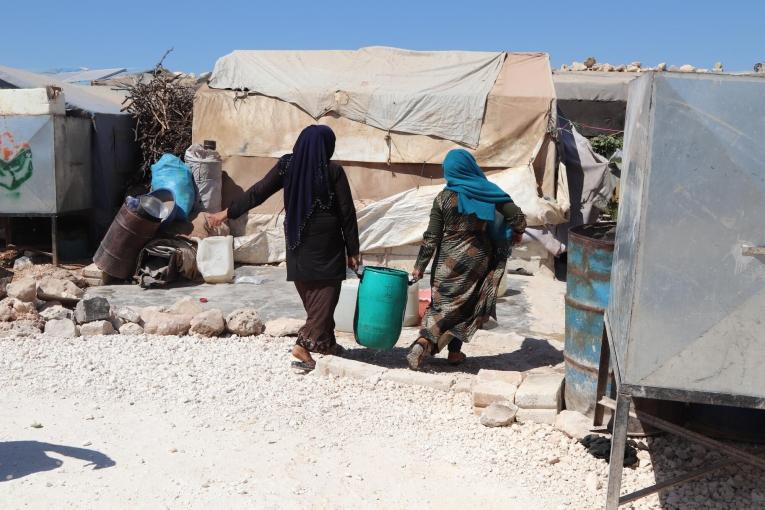 Des femmes habitant un camp pour personnes déplacées transportent de l'eau fournie par MSF. Syrie. 2021.
 © Abdurzaq Alshami