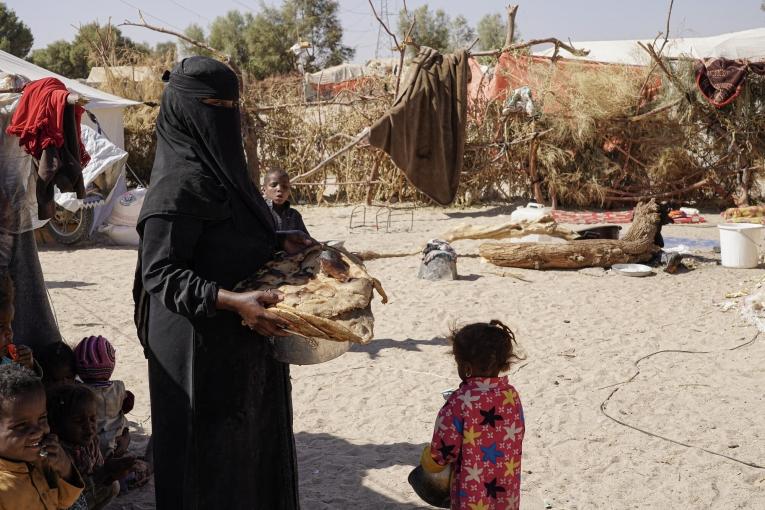Une femme transporte du pain pour le petit-déjeuner. Camp de déplacés à Al-Khuseif à Marib. Yémen. 2021.
© Hesham Al Hilali