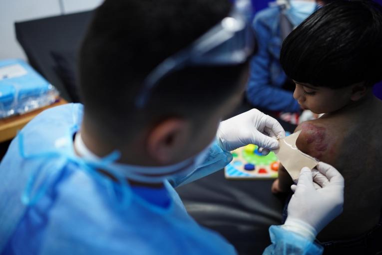 Un&nbsp;physiothérapeute MSF prépare un pansement additionnel pour Wadi, 3 ans. Gaza. 2021.
 © Tetiana Gaviuk/MSF