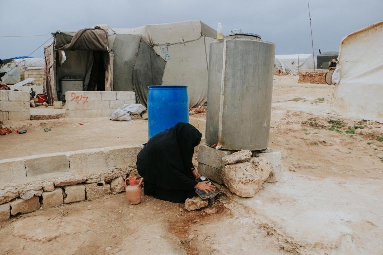 Une femme lave sa vaisselle dans un camp de personnes déplacées. Nord-ouest de la Syrie. 2022.
 © MSF/Abd Almajed Alkarh